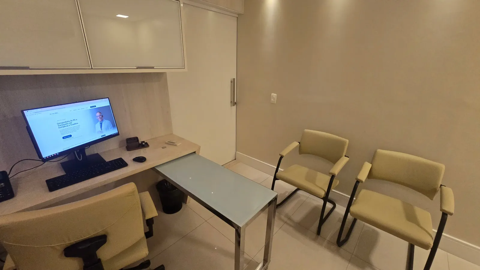 Mesa de atendimento do consultório em Fortaleza, com computador e cadeiras para a consulta