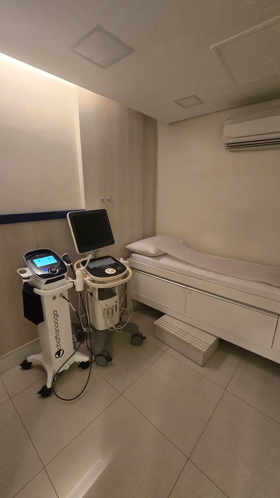 Sala de procedimentos do consultório em Fortaleza, com aparelho de ondas de choque, ultrassom e maca