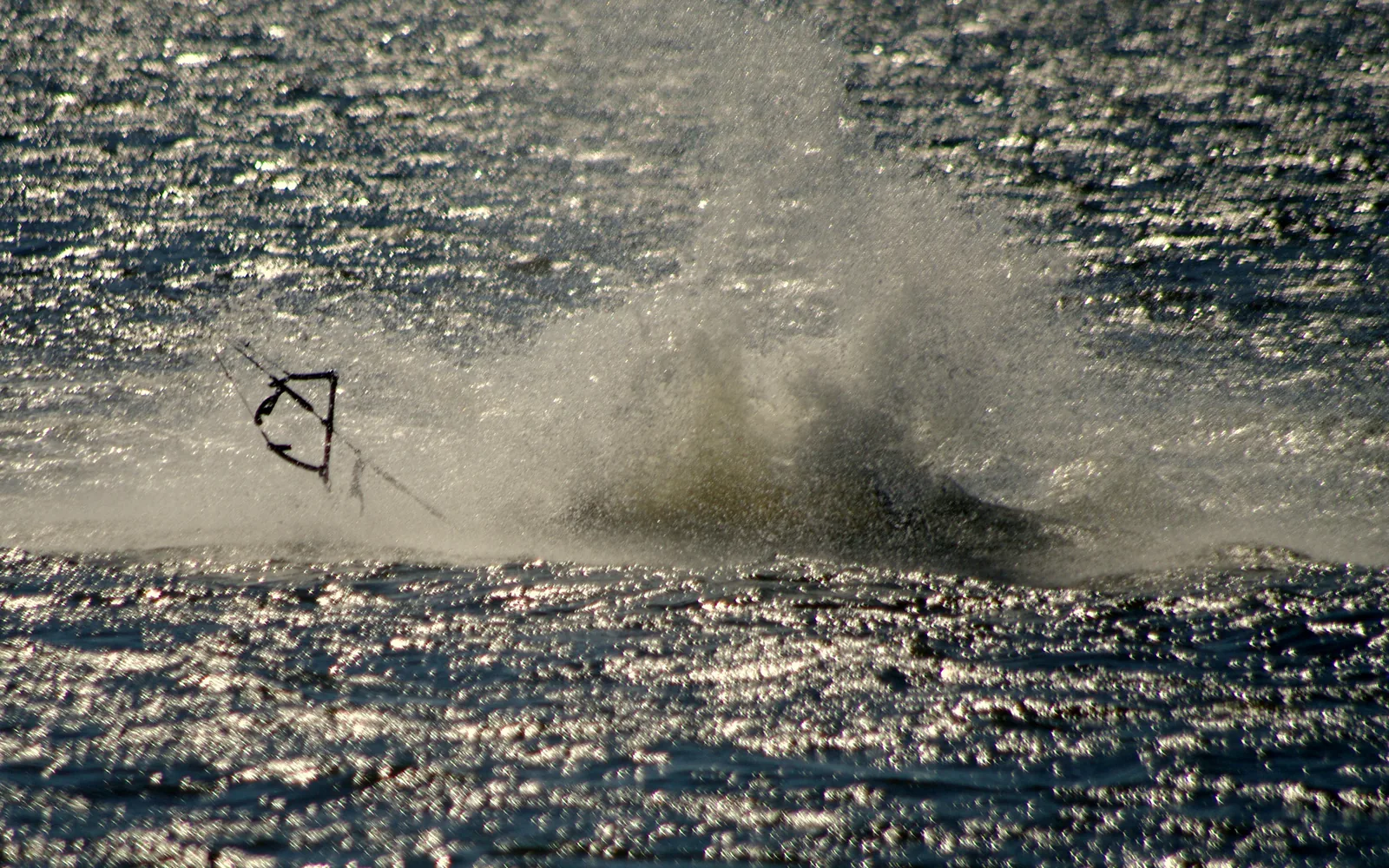 Kitesurfista caindo na água após um pouso malsucedido em competição, com a prancha solta ao lado — imagem ilustrativa
